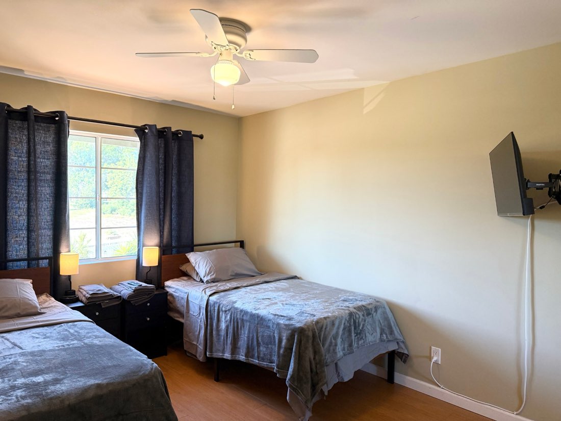 A second bedroom with two beds, a ceiling fan and a window to the garden