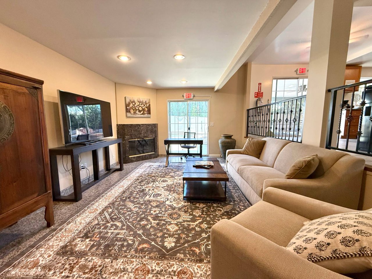 The living room, with a long sofa, a TV, a rug, a fireplace and glass doors to the yard